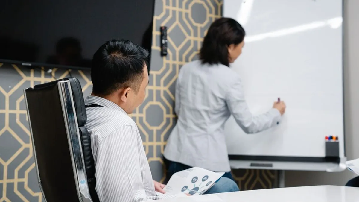 Business professionals engaging in a collaborative meeting using a whiteboard for brainstorming.